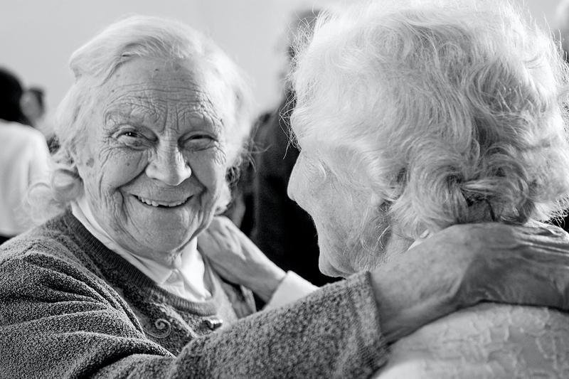 Two elderly aging women sharing a friendly hug