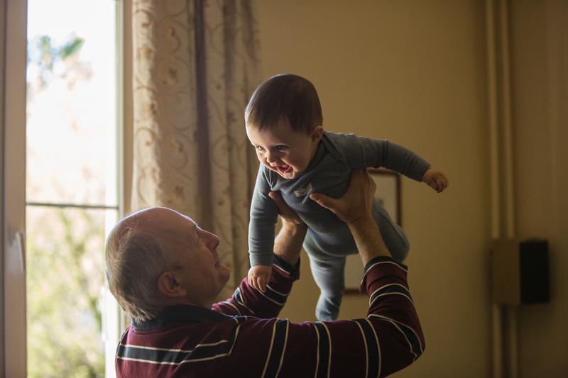 A baby in grandpa's arms, held overhead